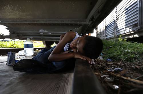A Honduran child rests under the train, in Arriaga, Chiapas, waiting to board The Beast. Photo: Alfredo Domínguez 