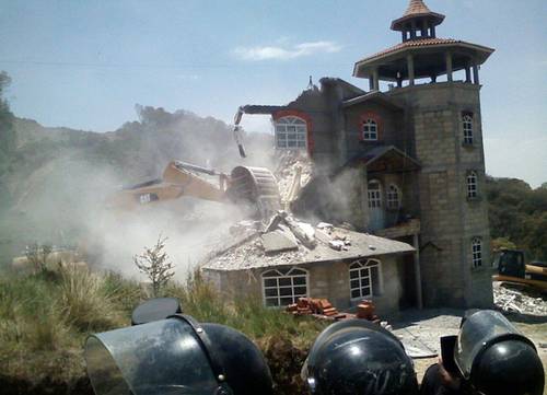 Protected by riot police, construction company's heavy equipment destroys a house in Xochicuautla. Photo: La Jornada